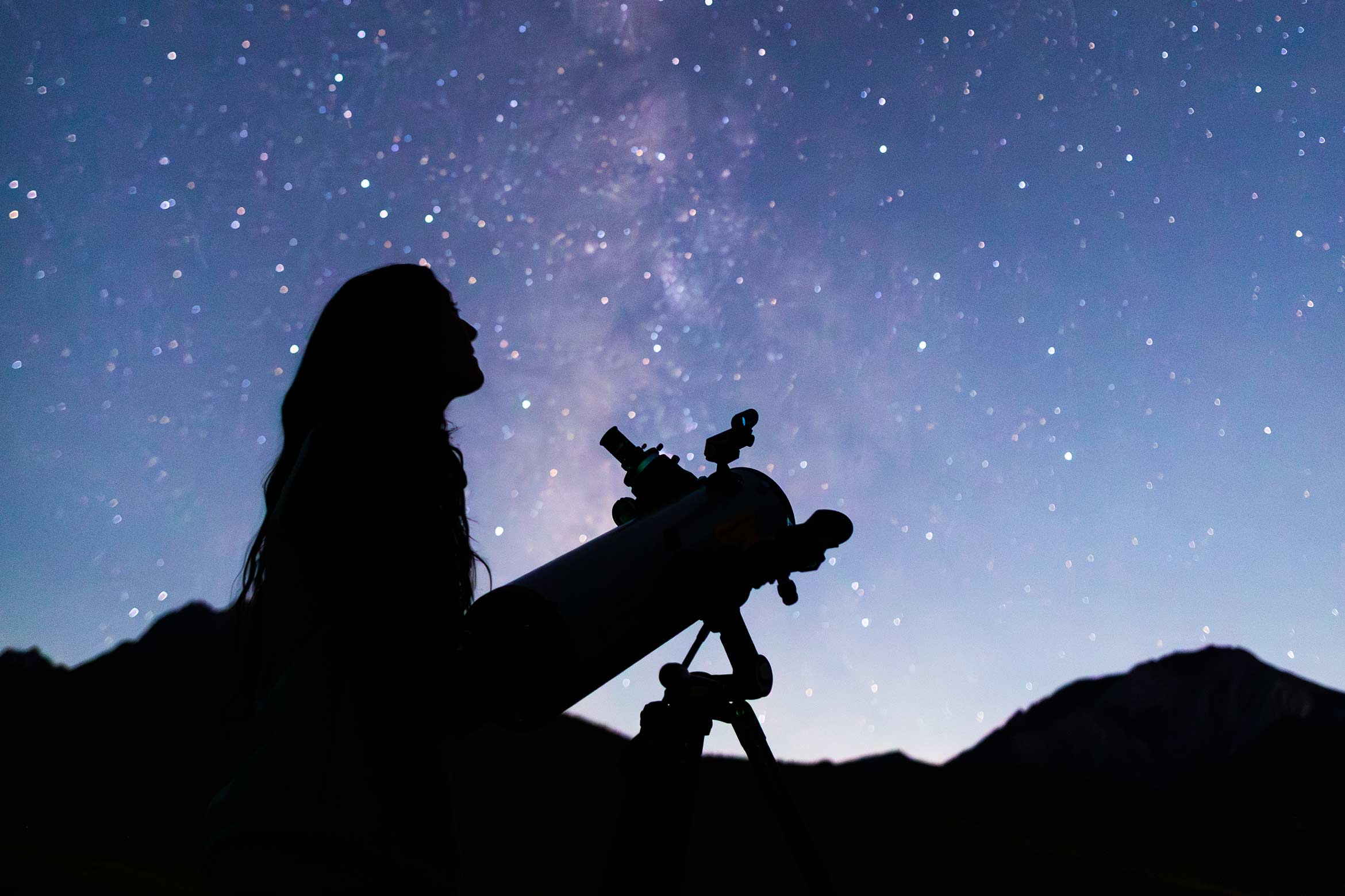 Fuerte student using telescope with starry sky behind